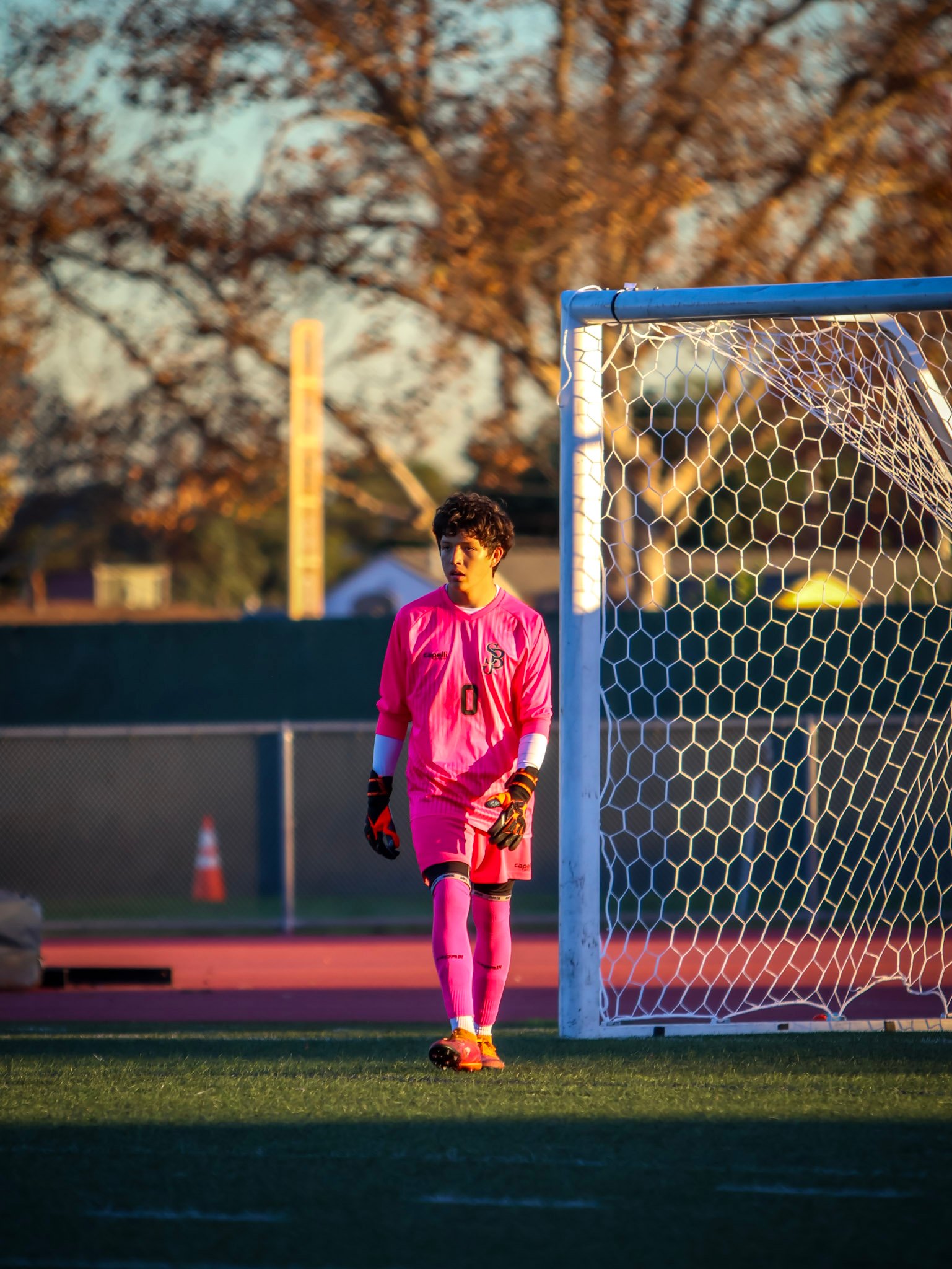 Goalkeeper in pink framed beside the goal