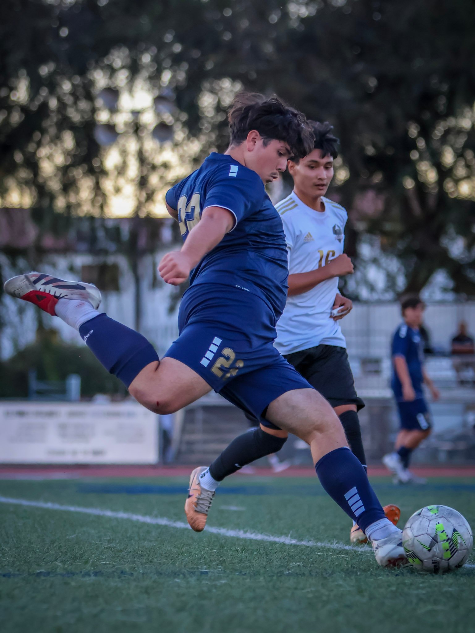 Soccer player striking the ball under pressure
